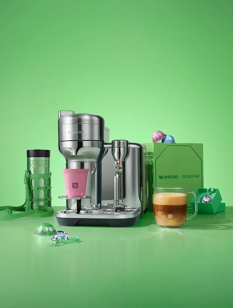 Green Nespresso x Swarovski travel mug with crystal-set holder beside a Nespresso machine