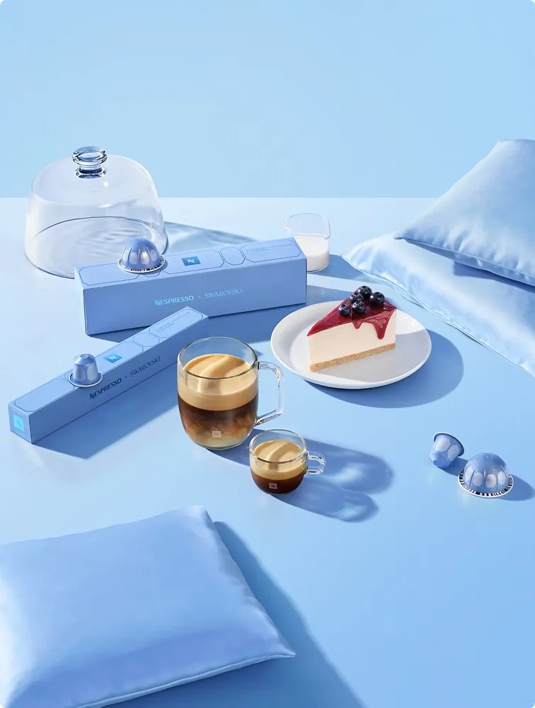 Blueberry Cheesecake flavored coffee with Original and Vertuo capsules and a slice of cheesecake